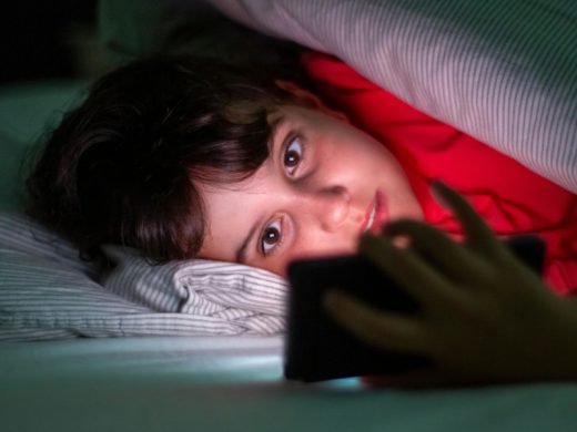 Мальчик под одеялом смотрит в телефон