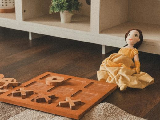 Тряпичная кукла и деревянные крестики-нолики лежат на полу