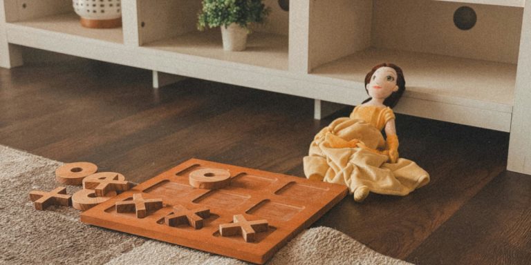 Тряпичная кукла и деревянные крестики-нолики лежат на полу