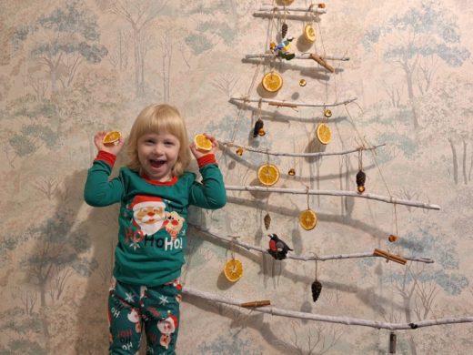Маленькая девочка у самодельной настенной ёлки