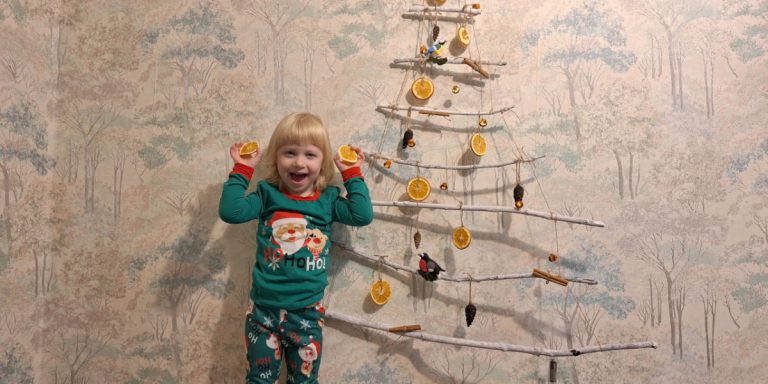 Маленькая девочка у самодельной настенной ёлки