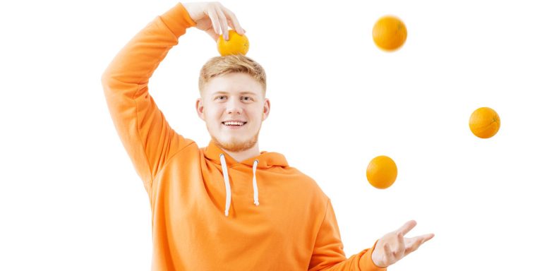 молодой человек жонглирует апельсинами