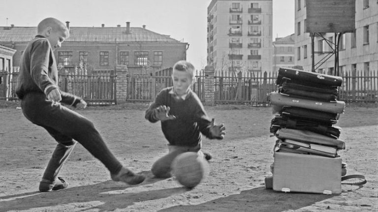 Двое детей играют в мяч на улице