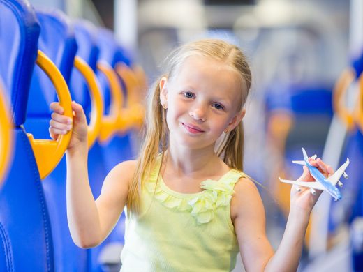Adorable little girl traveling on train and having fun with airplane model in hands