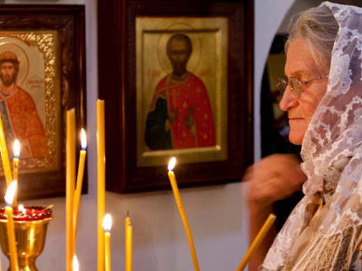 Женщина ставит свечи перед иконами