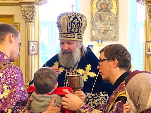 Священник причащает малыша